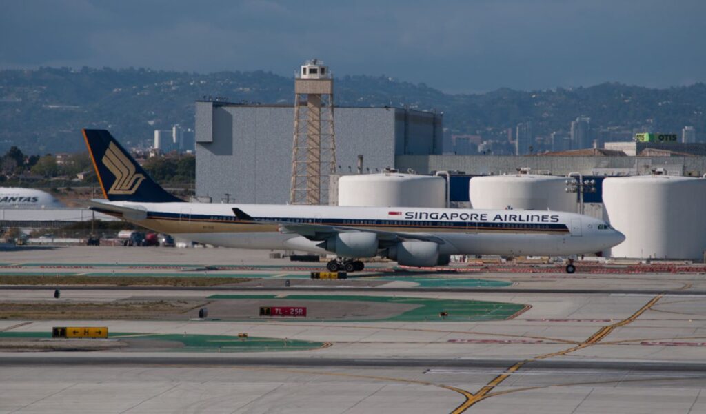Singapore Airlines plane on runway with cityscape in background.